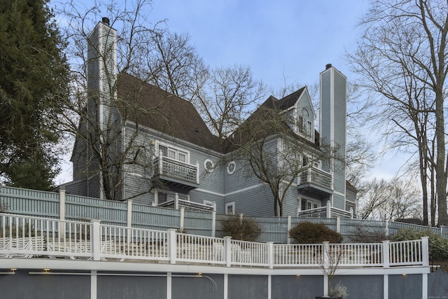 back of house with a chimney and fence