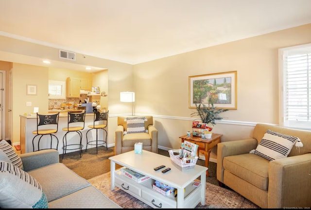 carpeted living area featuring visible vents and baseboards