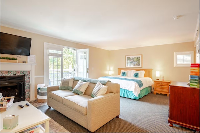 bedroom featuring carpet floors, multiple windows, a tile fireplace, and access to exterior