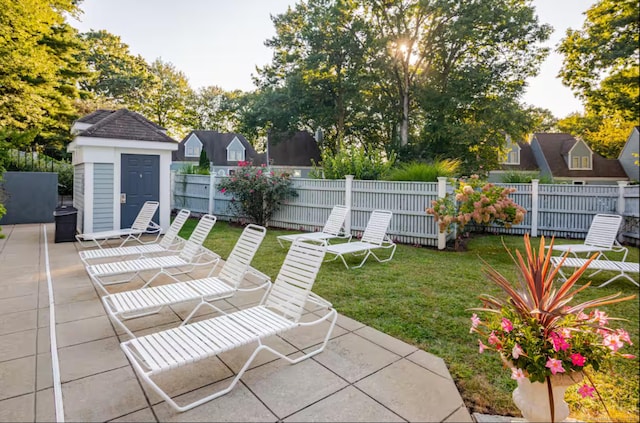 view of patio featuring a fenced backyard, a storage unit, and an outbuilding