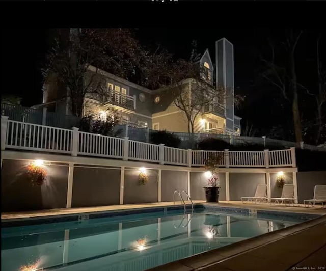 pool at twilight featuring a patio and a community pool