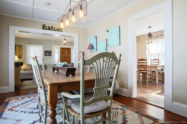 dining space featuring crown molding, baseboards, and hardwood / wood-style flooring