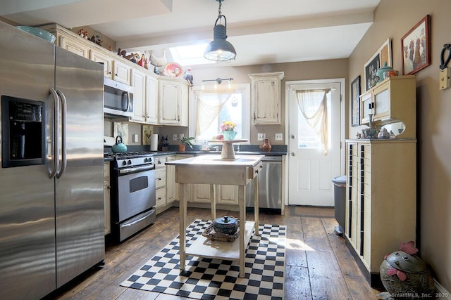 kitchen featuring dark countertops, a kitchen island, dark wood-type flooring, decorative light fixtures, and stainless steel appliances