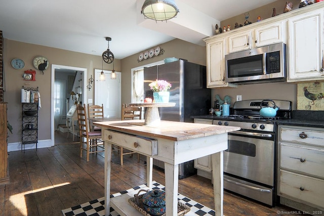 kitchen featuring dark wood-type flooring, baseboards, appliances with stainless steel finishes, dark countertops, and pendant lighting