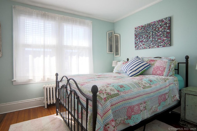 bedroom featuring ornamental molding, baseboards, radiator heating unit, and wood finished floors