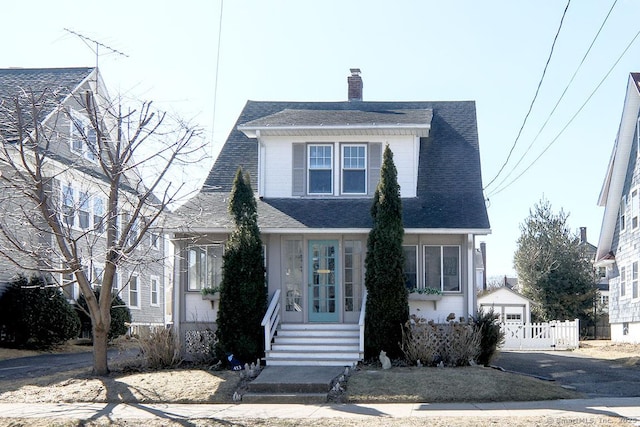 view of front of property with driveway, a chimney, fence, and roof with shingles