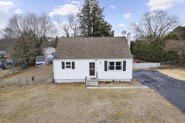 view of front of house featuring a shingled roof, entry steps, and fence