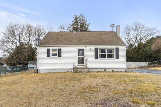 view of front of property featuring entry steps, roof with shingles, fence, and a front yard