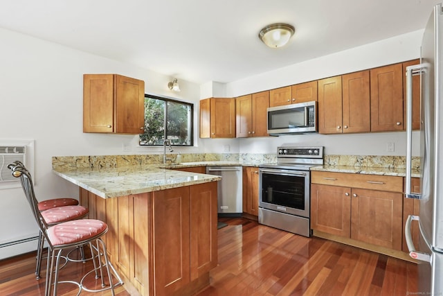 kitchen featuring appliances with stainless steel finishes, brown cabinetry, a peninsula, and a kitchen breakfast bar