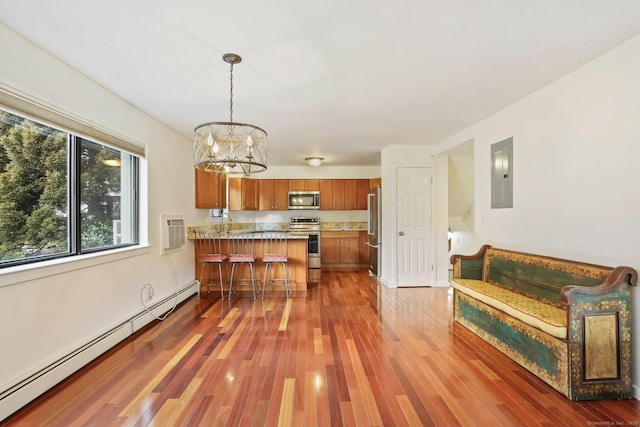 kitchen with a baseboard radiator, stainless steel appliances, a peninsula, electric panel, and brown cabinets