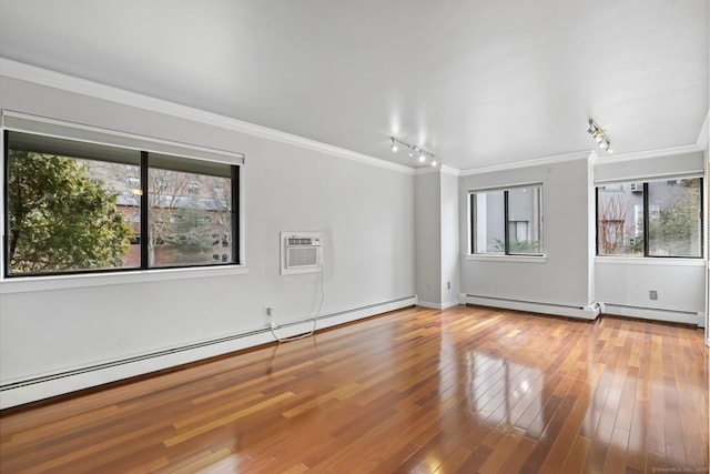 empty room featuring hardwood / wood-style floors, a baseboard radiator, and crown molding