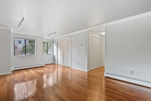 interior space with light wood-style floors, a baseboard radiator, ornamental molding, and baseboard heating