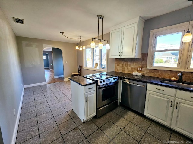 kitchen with arched walkways, visible vents, stainless steel appliances, white cabinetry, and a sink