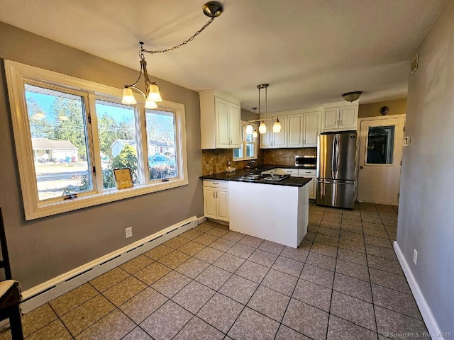 kitchen featuring tasteful backsplash, dark countertops, freestanding refrigerator, a peninsula, and baseboard heating