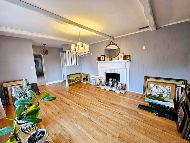 living room with a notable chandelier, wood finished floors, visible vents, beamed ceiling, and a tiled fireplace