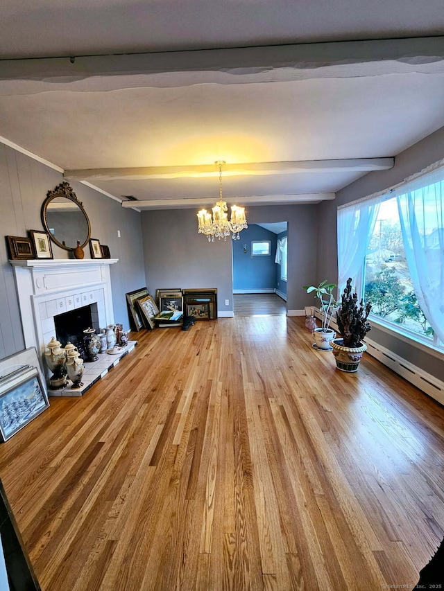 unfurnished living room with a tile fireplace, a notable chandelier, wood finished floors, baseboards, and beam ceiling