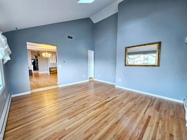 spare room with a baseboard heating unit, a chandelier, baseboards, and light wood finished floors