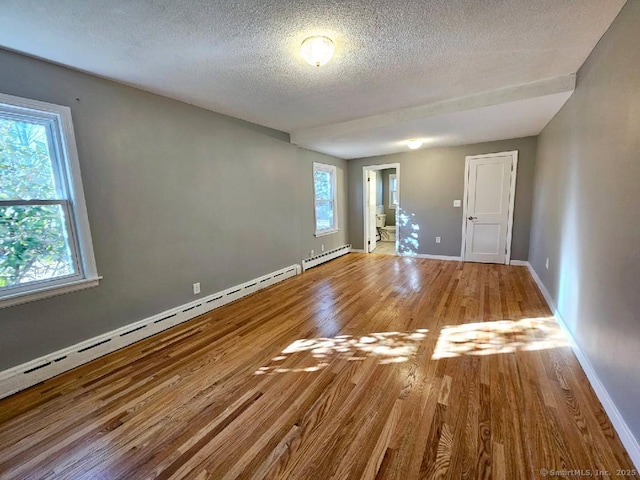 spare room featuring baseboards, a textured ceiling, baseboard heating, and wood finished floors