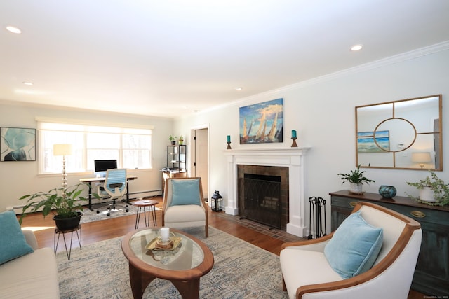 living area with ornamental molding, a tile fireplace, recessed lighting, and wood finished floors