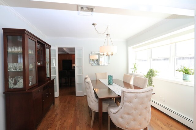 dining area featuring a baseboard heating unit, wood finished floors, visible vents, and crown molding