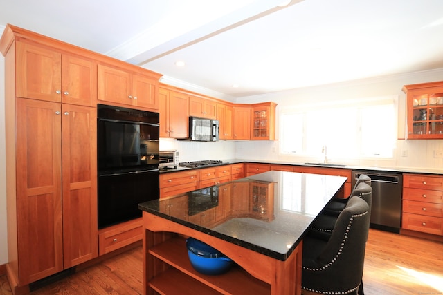 kitchen with open shelves, appliances with stainless steel finishes, glass insert cabinets, light wood-type flooring, and a kitchen breakfast bar