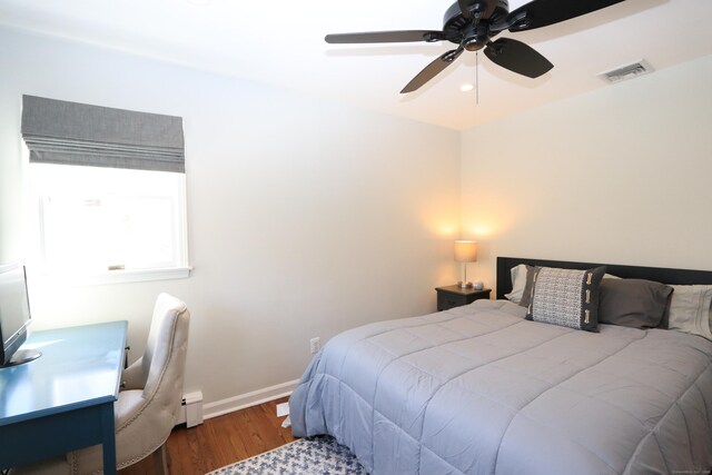 bedroom with baseboards, visible vents, ceiling fan, wood finished floors, and baseboard heating