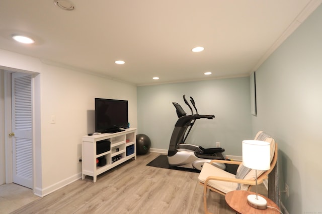 exercise area featuring baseboards, light wood finished floors, ornamental molding, and recessed lighting