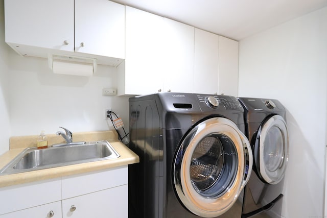 clothes washing area featuring washing machine and dryer, cabinet space, and a sink