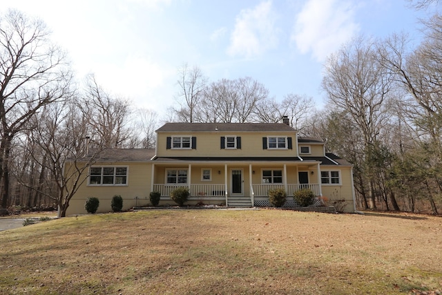 view of front of property with covered porch, a chimney, and a front yard