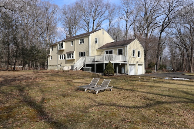 rear view of property with a chimney, aphalt driveway, an attached garage, stairs, and a wooden deck