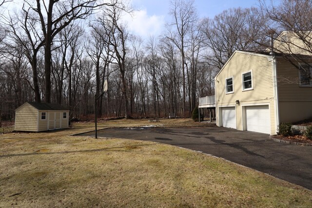 view of yard with a garage, driveway, a shed, and an outdoor structure