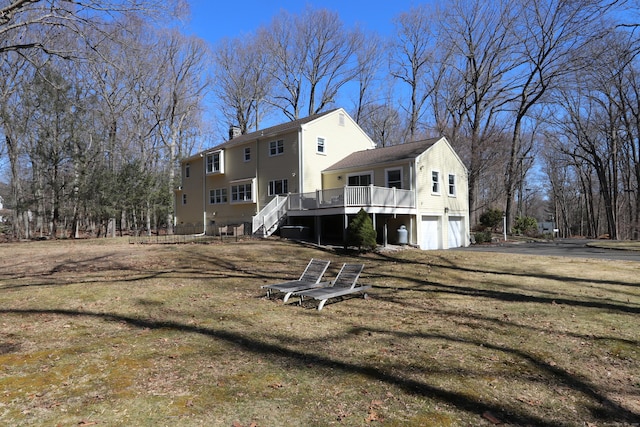 back of house with a deck, aphalt driveway, stairway, a garage, and a chimney