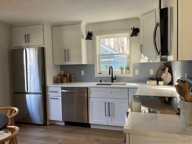 kitchen featuring appliances with stainless steel finishes, decorative backsplash, and light wood-style floors