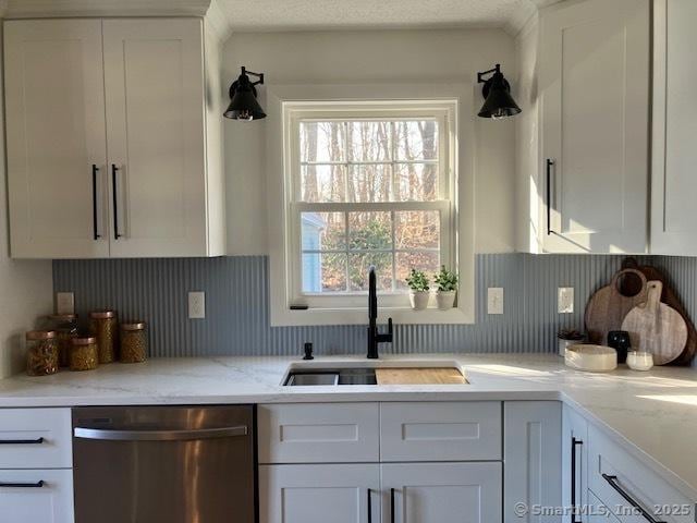 kitchen with decorative backsplash, white cabinets, dishwasher, a textured ceiling, and a sink