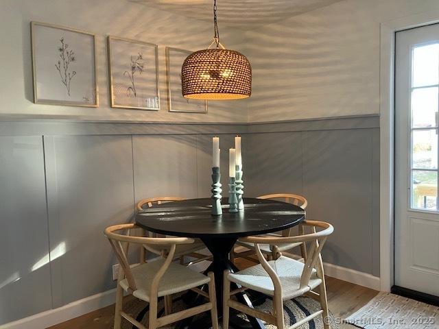 dining space with wood finished floors, a wealth of natural light, and a decorative wall