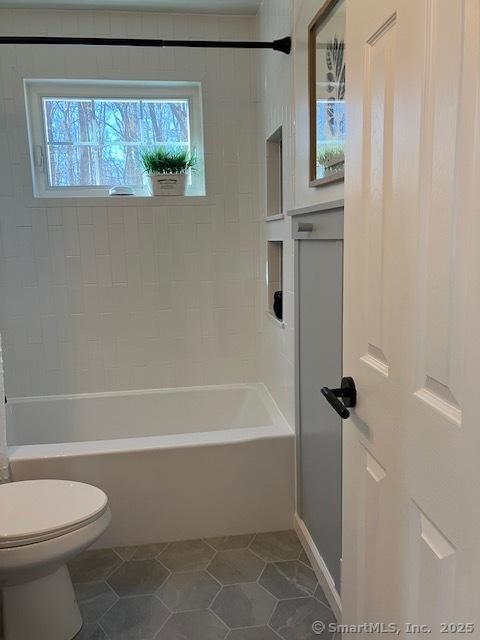 bathroom featuring toilet, tub / shower combination, and tile patterned floors