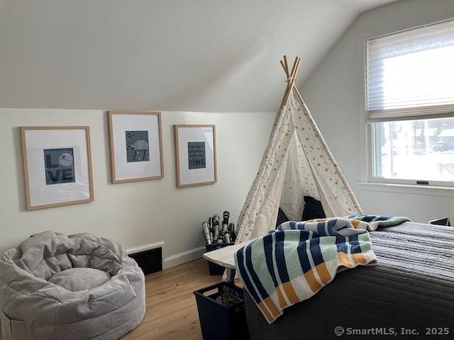 bedroom with vaulted ceiling, wood finished floors, and baseboards