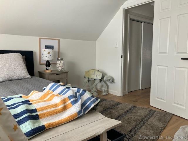 bedroom with vaulted ceiling and wood finished floors