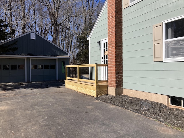 view of side of property featuring a garage, an outdoor structure, a chimney, and a wooden deck