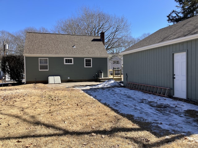 back of house with a patio area, a chimney, and roof with shingles