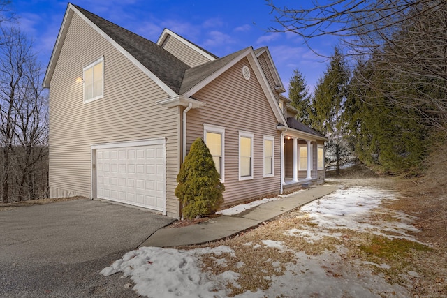 view of side of home featuring driveway and a shingled roof