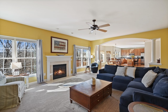 living room with a fireplace with flush hearth, light colored carpet, decorative columns, and baseboards