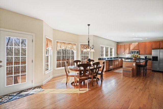 dining room with light wood-type flooring, an inviting chandelier, baseboards, and recessed lighting