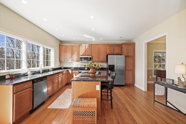 kitchen featuring stainless steel appliances, a center island, light wood-style flooring, and a kitchen breakfast bar