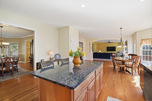 kitchen with light wood-type flooring, arched walkways, pendant lighting, and dishwasher