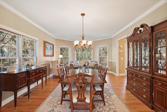 dining space with light wood-style floors, a chandelier, and crown molding