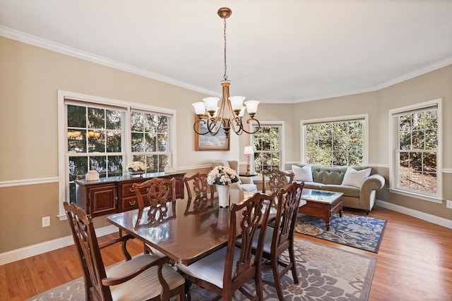 dining space with ornamental molding, light wood-style flooring, baseboards, and an inviting chandelier