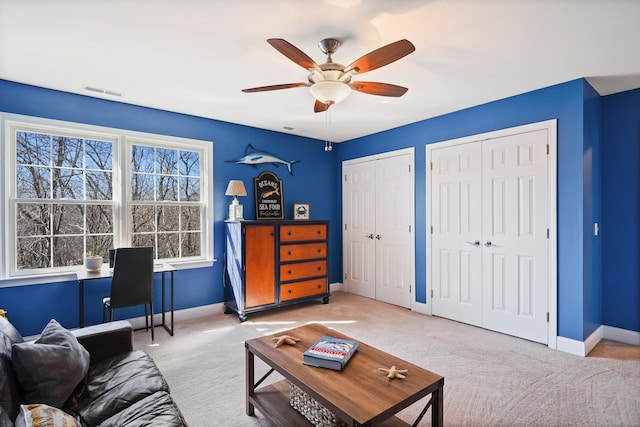 carpeted living room with a ceiling fan, visible vents, and baseboards