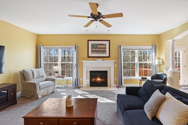 living room with carpet, decorative columns, a ceiling fan, a high end fireplace, and baseboards