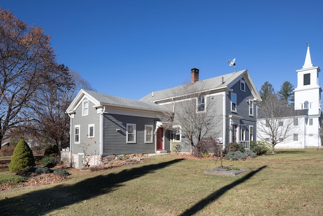 back of house featuring a lawn and a chimney